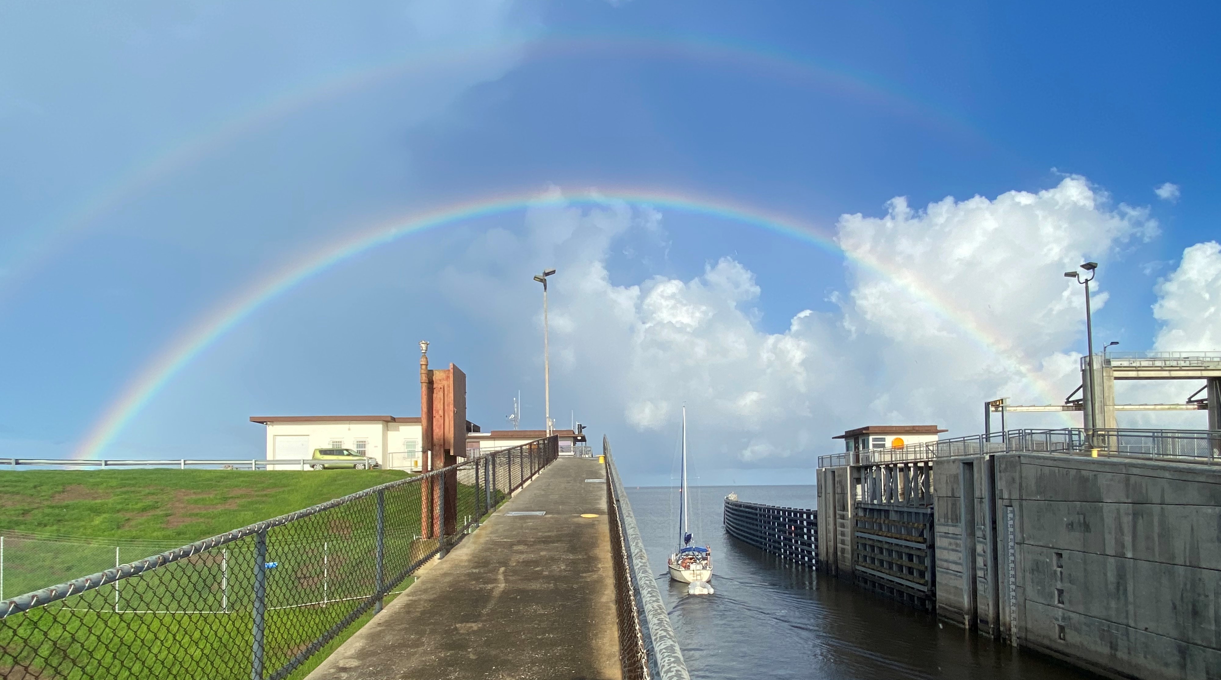 Photo of sailboat locking through the Port Mayca Lock and Dam into Lake Okeechobee with double rainbow